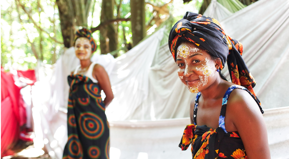 Femme africaine portant un maquillage traditionnel blanc et une tenue color&eacute;e lors d'une c&eacute;r&eacute;monie culturelle &agrave; Madagascar.